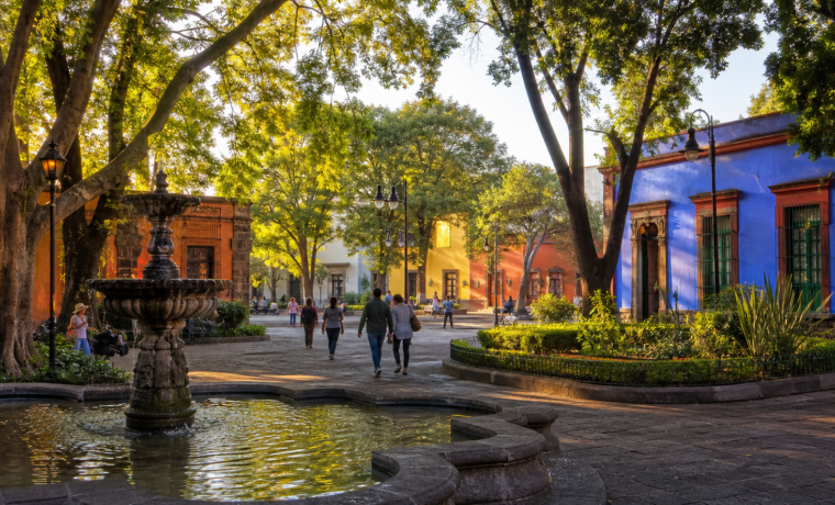 Plaza arbolada de Coyoacán con fuente y arquitectura histórica al amanecer